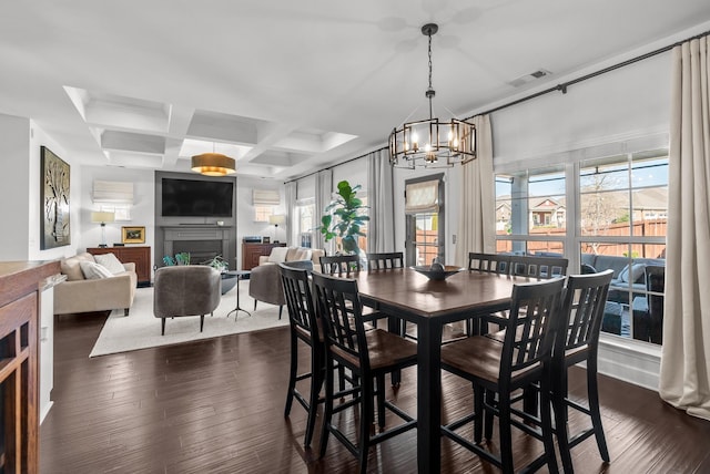 dining room with visible vents, coffered ceiling, dark wood-style floors, a fireplace, and beam ceiling