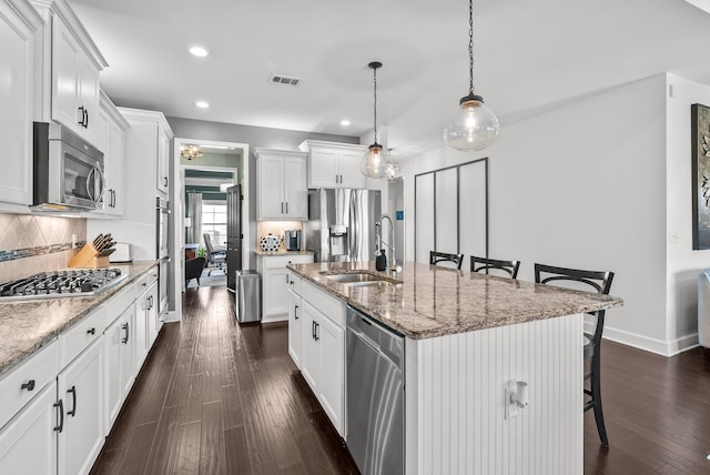 kitchen featuring visible vents, appliances with stainless steel finishes, a kitchen breakfast bar, a sink, and backsplash