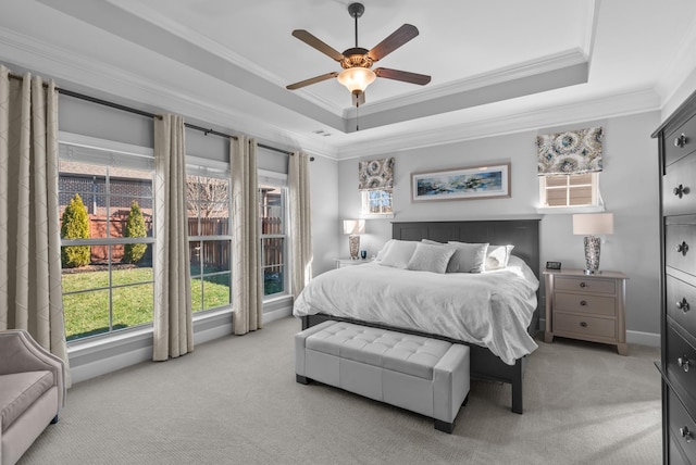 bedroom with ornamental molding, a raised ceiling, and light colored carpet