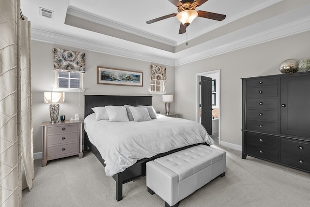 bedroom with light colored carpet, visible vents, baseboards, a tray ceiling, and crown molding