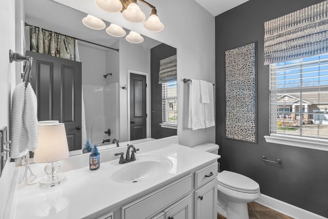 bathroom with a shower, a wealth of natural light, vanity, and toilet