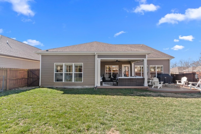 rear view of property with an outdoor living space with a fire pit, a yard, a patio, a ceiling fan, and a fenced backyard