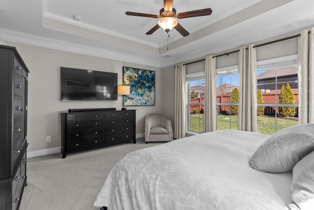 bedroom featuring crown molding, a tray ceiling, baseboards, and light colored carpet