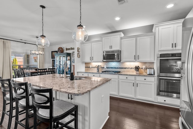 kitchen with stainless steel appliances, white cabinets, a sink, and backsplash