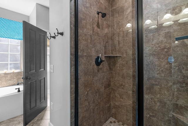 bathroom with a stall shower, tile patterned flooring, and a bath