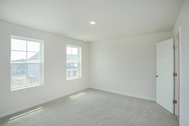 unfurnished room with light carpet and baseboards