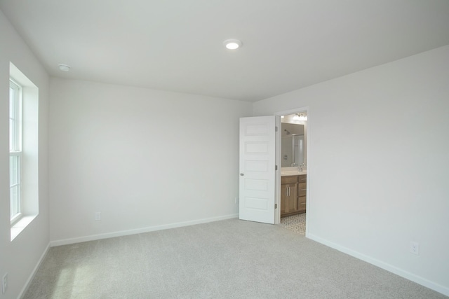 empty room featuring light carpet and baseboards