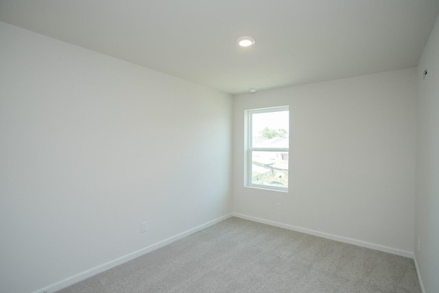 empty room featuring recessed lighting, light carpet, and baseboards