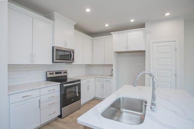 kitchen with white cabinetry, stainless steel appliances, and a sink