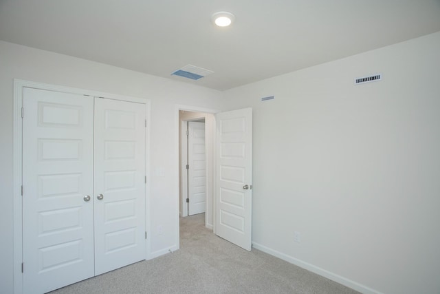 unfurnished bedroom featuring light carpet, a closet, visible vents, and baseboards