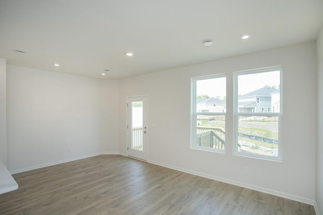 unfurnished room with baseboards, wood finished floors, and recessed lighting