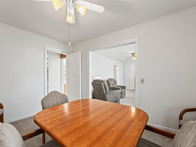 dining area featuring crown molding, carpet flooring, a ceiling fan, and baseboards