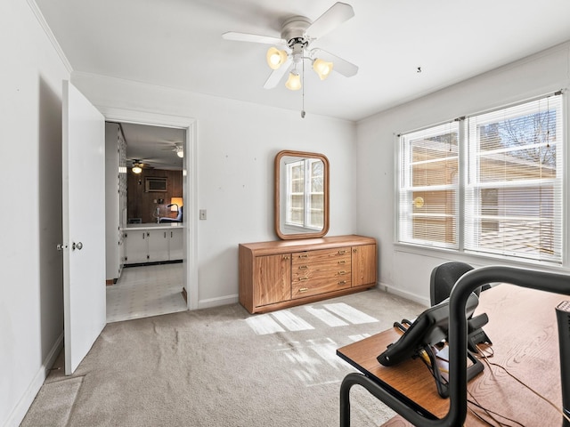 home office with light carpet, a ceiling fan, and baseboards