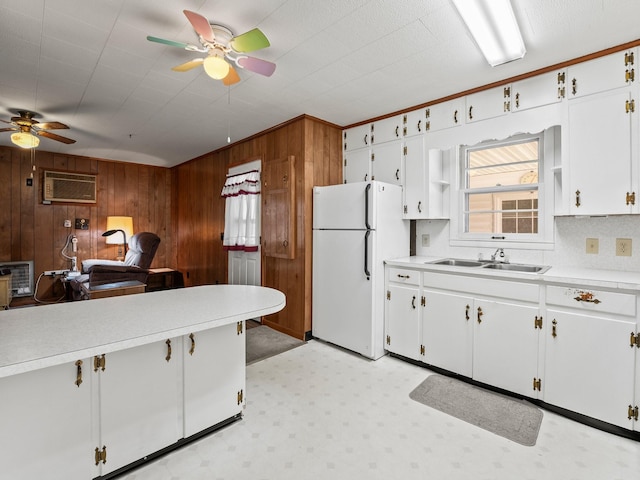 kitchen featuring wood walls, a sink, light countertops, freestanding refrigerator, and light floors