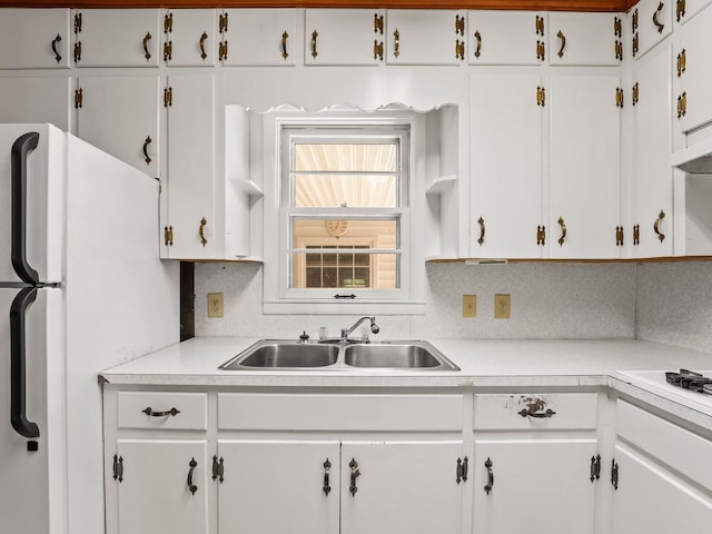 kitchen with white cabinets, white appliances, light countertops, and a sink