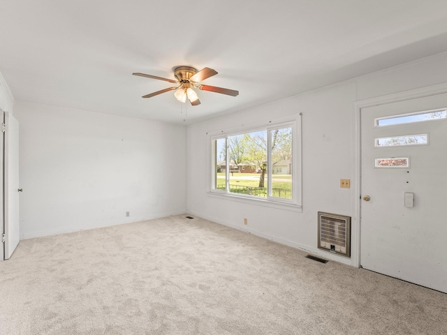 spare room featuring carpet flooring, a ceiling fan, visible vents, and heating unit