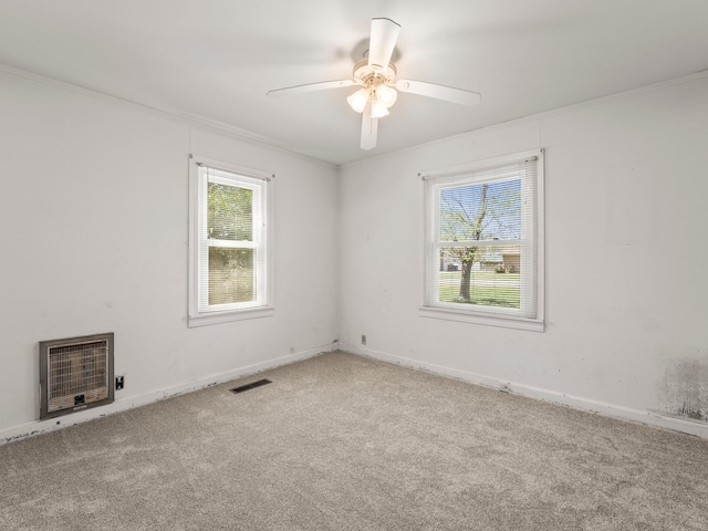 empty room featuring carpet, visible vents, heating unit, and a healthy amount of sunlight