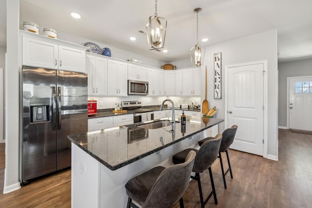 kitchen featuring dark wood-style floors, a breakfast bar, stainless steel appliances, white cabinetry, and a sink