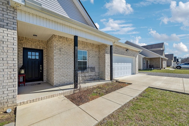 entrance to property featuring an attached garage, a porch, concrete driveway, and brick siding