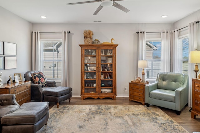 living area featuring a healthy amount of sunlight, visible vents, baseboards, and wood finished floors