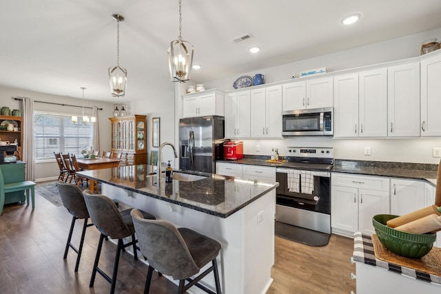 kitchen featuring stainless steel appliances, a sink, visible vents, white cabinetry, and a kitchen breakfast bar