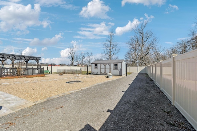 view of yard with an outbuilding, driveway, a fenced backyard, and a pergola