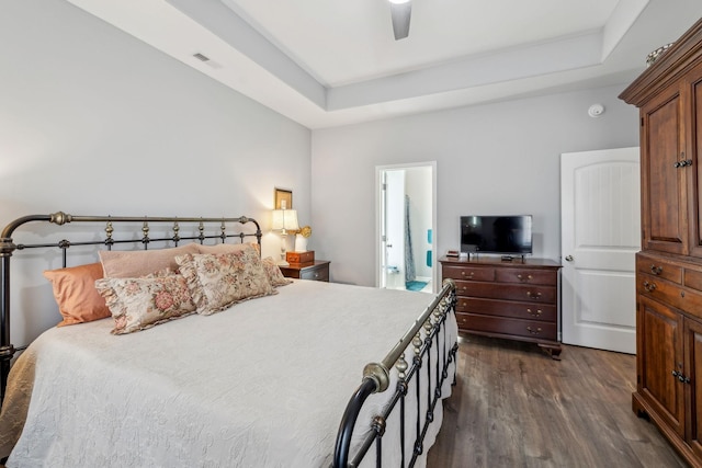 bedroom featuring ceiling fan, a tray ceiling, dark wood-style flooring, and visible vents