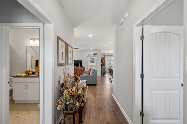 hallway with recessed lighting, a sink, baseboards, and wood finished floors