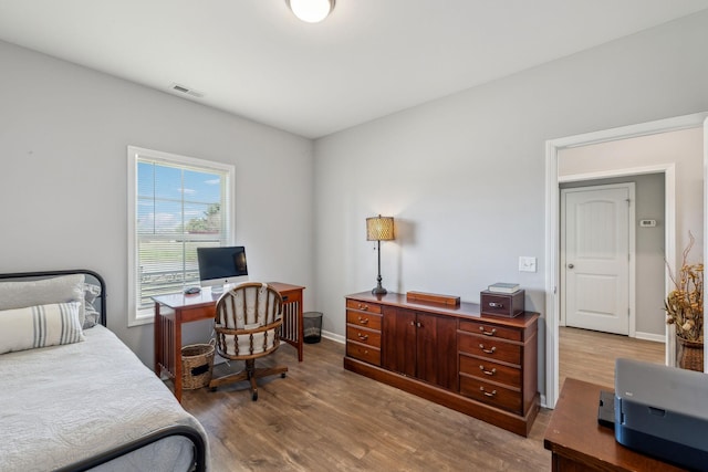 bedroom with wood finished floors, visible vents, and baseboards