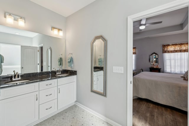 ensuite bathroom featuring double vanity, baseboards, a sink, and ensuite bathroom