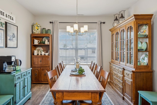 dining area with wood finished floors and a notable chandelier