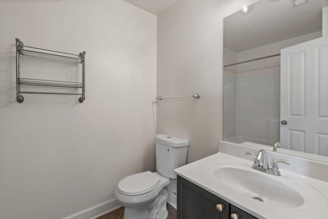 bathroom featuring a shower, baseboards, vanity, and toilet