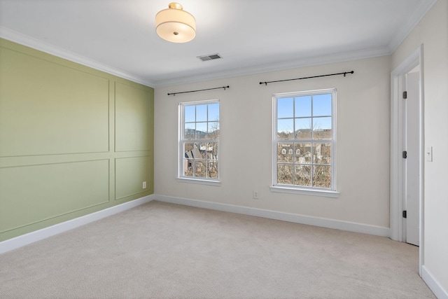 spare room with baseboards, light colored carpet, visible vents, and crown molding