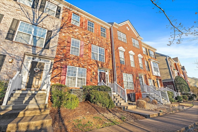 townhome / multi-family property featuring central AC and brick siding