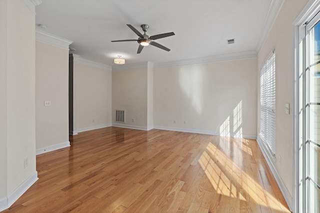 spare room with light wood finished floors, baseboards, visible vents, and crown molding