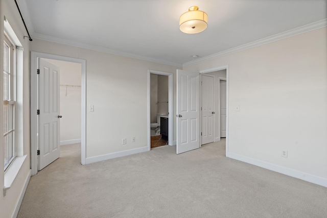 unfurnished bedroom featuring light carpet, baseboards, a walk in closet, and crown molding