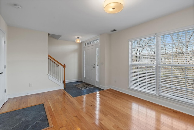 entrance foyer with baseboards, visible vents, stairway, and hardwood / wood-style floors