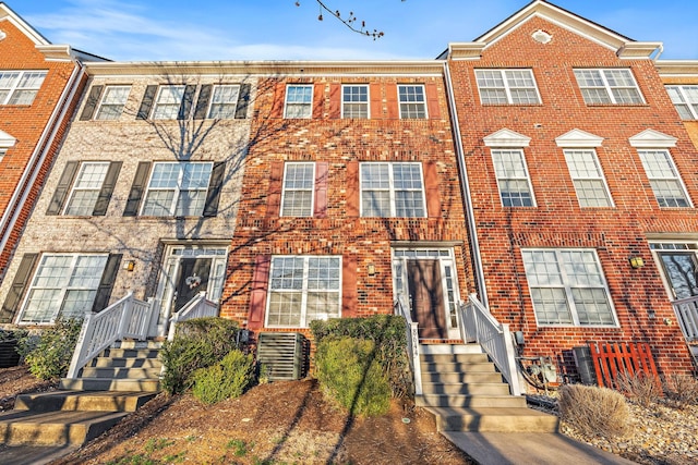 view of property with brick siding and central AC unit