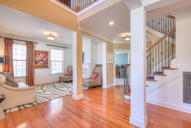 living room featuring baseboards, stairway, wood finished floors, and crown molding