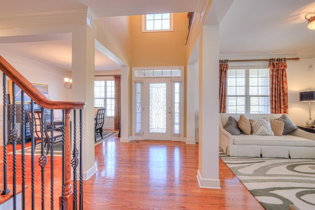 entryway with stairway, wood finished floors, and crown molding