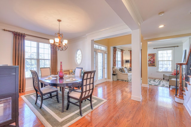 dining space featuring crown molding, light wood finished floors, stairway, an inviting chandelier, and baseboards