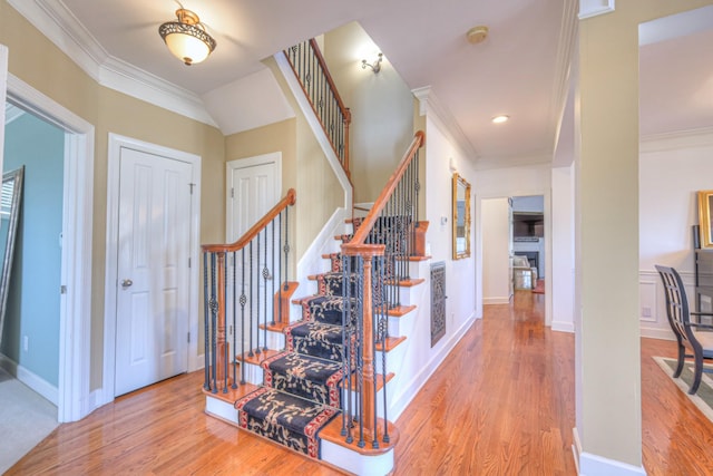 stairs with baseboards, a fireplace, ornamental molding, and wood finished floors