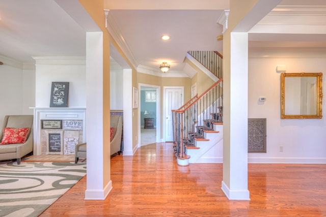 entryway with ornamental molding, stairway, wood finished floors, and baseboards