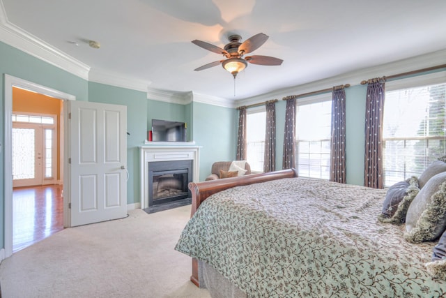 bedroom featuring a fireplace with flush hearth, multiple windows, crown molding, and carpet floors