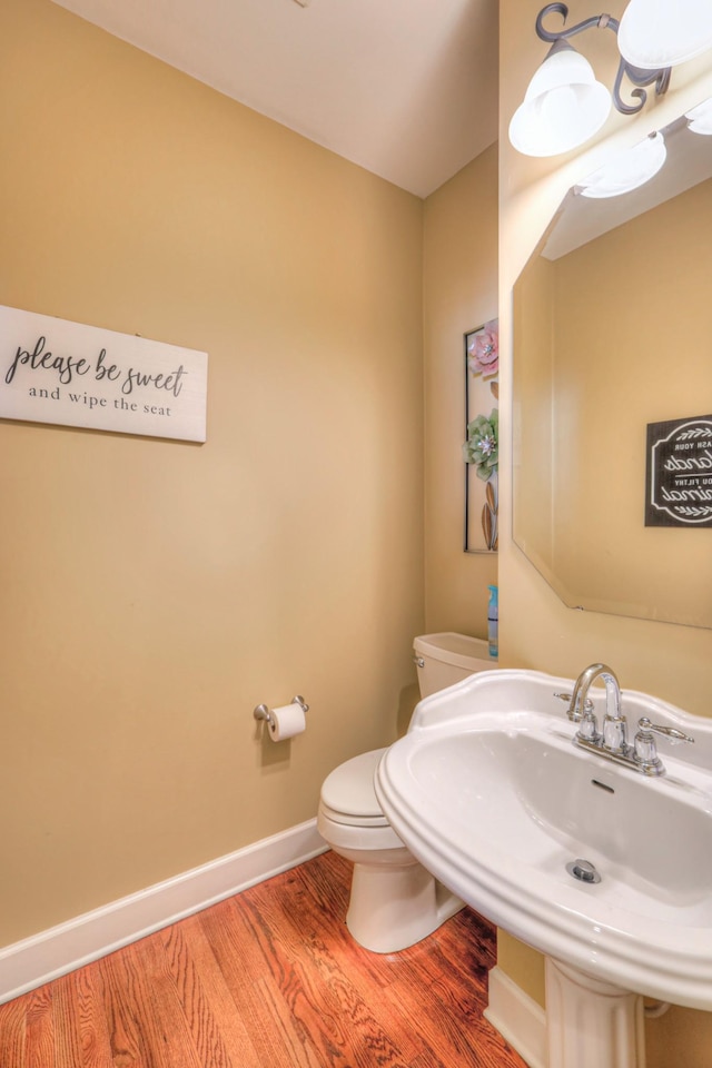 bathroom featuring a sink, wood finished floors, toilet, and baseboards