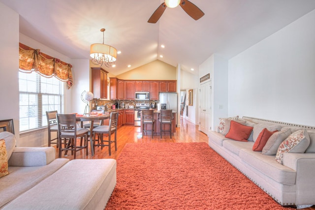 living area with lofted ceiling, light wood-type flooring, ceiling fan with notable chandelier, and recessed lighting