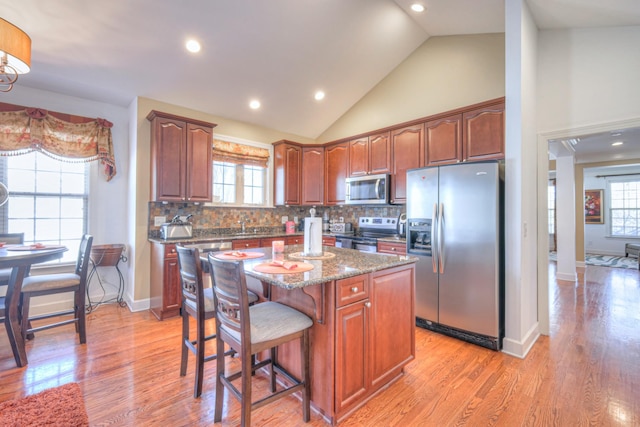 kitchen featuring stainless steel appliances, light wood-type flooring, a kitchen island, and a wealth of natural light