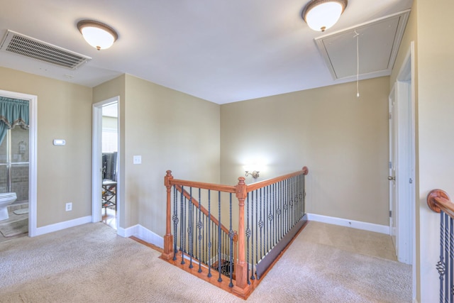 hall featuring visible vents, carpet flooring, an upstairs landing, and attic access