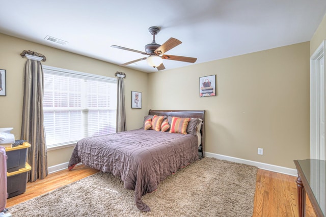 bedroom featuring a ceiling fan, baseboards, visible vents, and wood finished floors