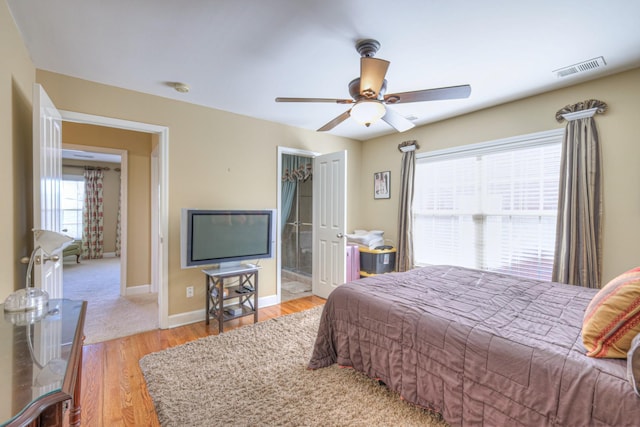 bedroom featuring a ceiling fan, visible vents, baseboards, and wood finished floors